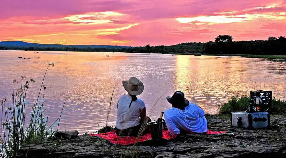 Couple relaxing by the river in Serengeti with a sunset view