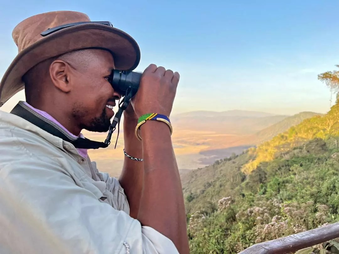 A safari guide scanning the Ngorongoro Conservation Area floor at golden hour